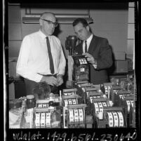 Toy slot machines manufacturer watching police Sgt. Robert H. Griffin inspecting the machines in Los Angeles, Calif., 1965