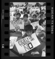 Parents and children with bilingual signs reading "Year Around School No" in Los Angeles, Calif., 1986