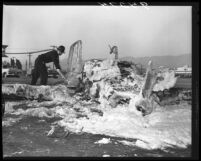 Firefighter hosing down wreckage of crashed plane that killed actor Robert Francis at Lockheed Air Terminal, Calif., 1955