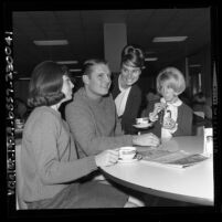 UCLA football player Kurt Altenberg taking a break with three coeds in UCLA Student Union, 1965