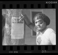 Michael Zinzun next to police brutality flyer, 1986