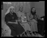 Priest Mary Meyer, center, holds picture of slain Krishna Venta. Flanking her are Bishop Nekona, left, and Bishop Asaiah, who temporarily assumed leadership of Fountain of the World after the leader was killed, 1958