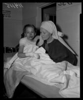 Linda Lee Baker with her grandmother, Sister Ruth Lewis, at Northridge Hospital after the 9-year-old suffered burns from a bombing of the Fountain of the World headquarters, 1958