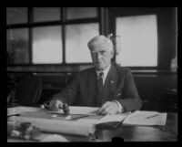 R. F. McLellan, County Supervisor, seated at his desk with a gavel, Los Angeles, 1927