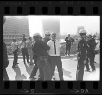 Man arrested as press watch outside of Century Plaza Hotel prior to demonstration during President Johnson's visit. A. 1967