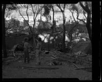 Fountain of the World leader's surviving son stands in the ruins of the sect's headquarters with another child. A. 1958