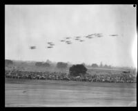 Biplanes fly in formation over spectators at United Airport in Burbank, 1930