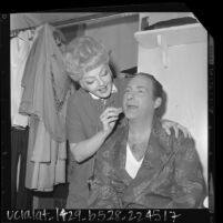 Nancy Andrews applying makeup to Sid Caesar backstage before "Little Me" show at Philharmonic Auditorium, Los Angeles, Calif., 1964