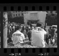 People, including two brothers wearing "Pray for Bobby" stickers on their backs, waiting outside hospital for news about Robert F. Kennedy, Los Angeles, Calif., 1968