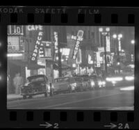 City street scene with neon signs of bars, hotels and theatres along skid row in Los Angeles, Calif., 1965