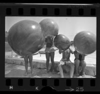 Four children hiding behind plastic balloons at Griffith Park, Los Angeles, 1970