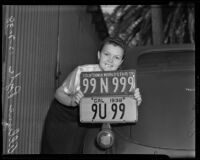 Allyne Pyle holds a license plate for 1938 under the model for the new 1939 license plate, Los Angeles, 1938