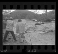 Boat with children is pulled across flooded Topanga Creek by a cable, Topanga, 1969