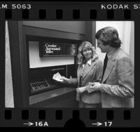 Couple demonstrating a Crocker Bank Automated Teller machine (ATM), Calif., 1977