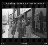 People reading "Fun in Space" article about "Star Wars" movie posted at Avco Center cinema in Westwood, Calif., 1977