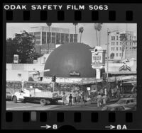 Pickets with placards reading "Save the Derby" in front of Brown Derby restaurant that's wrapped in scaffolding, Los Angeles, Calif., 1980