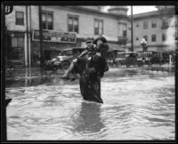 Policeman carrying woman across flooded street, [Los Angeles County?], 1926