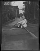 Actress Lona Andre navigating a rowboat through the flooded streets of Paramount Studios, Los Angeles, 1933