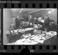 Police investigators displaying guns, office equipment and credit cards recovered in sting operation in Los Angeles, Calif., 1986