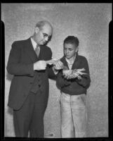 Ernest W. Fischer Jr. holds a carrier pigeon while Mayor P. H. McQuillen reads a letter, Upland, 1936