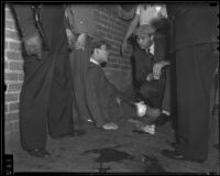 Pedro Garong speaks with Officer R. W. Clark after being shot by gang members in Ferguson Alley, Chinatown, Los Angeles, 1936