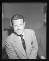 Tom Neal smiles to the camera in District Attorney S. Ernest Roll's office during questioning regarding his fight with Franchot Tone, 1951