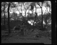 Fountain of the World leader's surviving son stands in the ruins of the sect's headquarters with another child. B. 1958