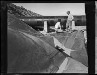 Two men stand atop a blast-damaged section of the Los Angeles Aqueduct in No-Name Canyon, Inyo County vicinity, [about 1927]