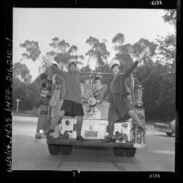 Two women on fire engine, modeling college "back to school" fashions, corduroy pea jacket and skirts, Los Angeles, Calif., 1962