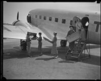 Five women transport fashion show outfits from airplane on runway, Los Angeles, 1935