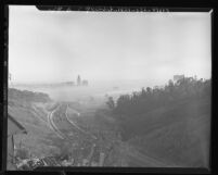 Looking down from the hills of Arroyo Seco Parkway at Los Angeles City Hall and Civic Center buildings surrounded by smog, 1948