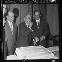 Los Angeles County Sheriff Pete Pitchess watches retired sheriff Eugene Biscailuz sample his 82nd birthday cake, 1965