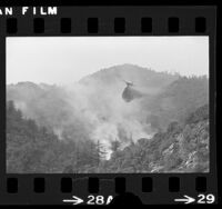 DC-6 airplane dropping fire retardant on wildfire near Mount Baldy Village, Calif., 1975