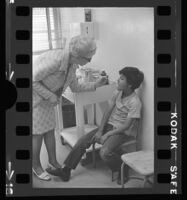 School nurse Nina Melching takes the temperature of Jesse Orona, East Los Agneles, 1972