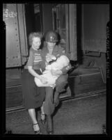 California National Guardsmen Dan Steelman seated in doorway of train with his wife and baby son, 1950