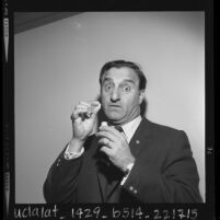 1/2 length portrait of comedian Danny Thomas with pills he takes for his voice, 1963
