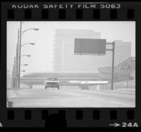 American Airlines plane taxiing on overpass above Sepulveda Blvd. as automobile drives down street in Los Angeles, Calif., 1976