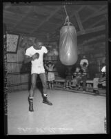 Boxer Ike Williams punching bag as children look on during training at Soper's Ranch, Calif., 1948