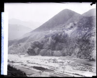 Cloud of dust and debris cascading down San Gabriel Canyon wall after an explosion during dam construction, Los Angeles County, 1929