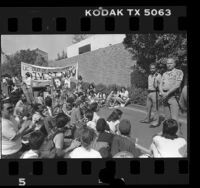 UCLA students in sit-down protest with banner reading "UC Out of South Africa! Divest Now" as two UC Police officers watch Los Angeles, Calif., 1986