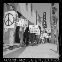 Marchers with signs reading "Have A Dream", "We Mourn Dr King" and the peace symbol walking down sidewalk in Van Nuys, Calif., 1968