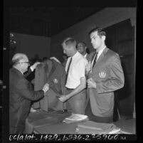 U.S. Olympic athletes Jerry Shipp and Bill Bradley receiving team jackets by official George J. Gulack, 1964