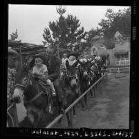 Walt Disney and granddaughter, Tammy Miller, riding burro at Disneyland, Anaheim, 1960