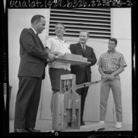 Peace Corps directors Dr. Robert H. Ewald and Dr. Robert Callahan with two trainees using brick making machine in Los Angeles, Calif., 1964