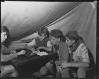 Boy Scouts in a tent at a camping event in a park, circa 1935