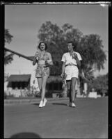 Lucy "Dickey Dell" Doheny and Joyce Hodgeson enjoy ice cream as they walk down a street, Palm Springs, 1936