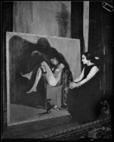 Artist Maroussia Valero seated before her painting of a sleeping nude, circa 1932