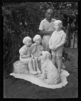 Ernest Yerbysmith standing next to his sculpture of 3 children with their dog, Los Angeles, 1935