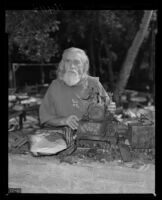 Patriarch Wilber Foster Yates stands among some remnants of the headquarters of Fountain of the World. A. 1958