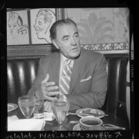 Author Louis L'Amour seated at restaurant table during interview in Los Angeles, Calif., 1970